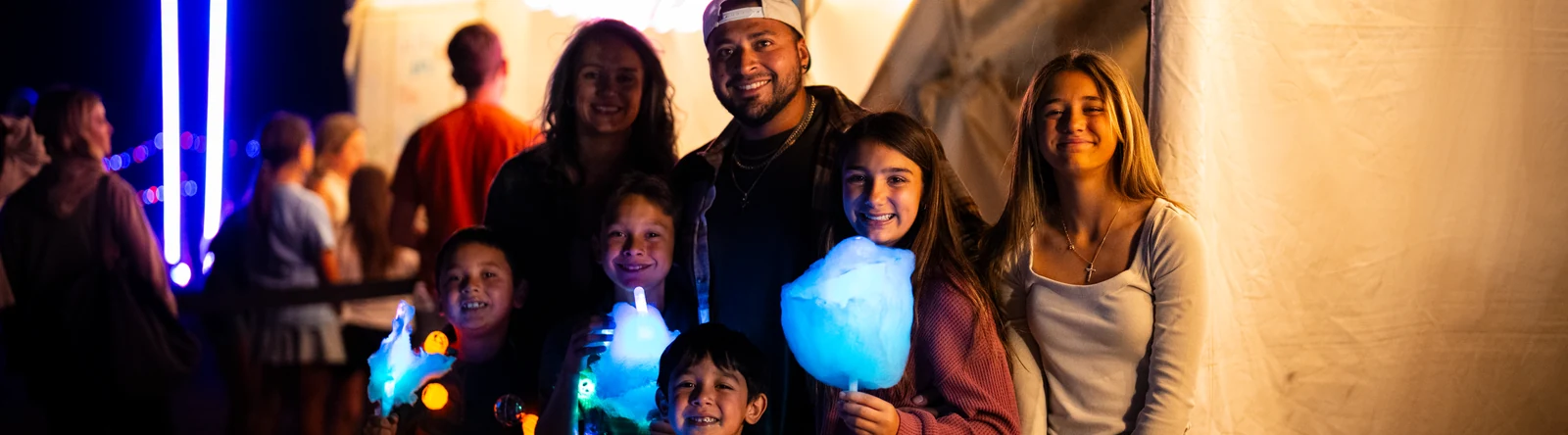 Families holding glowing cotton candy in Pumpkin Village