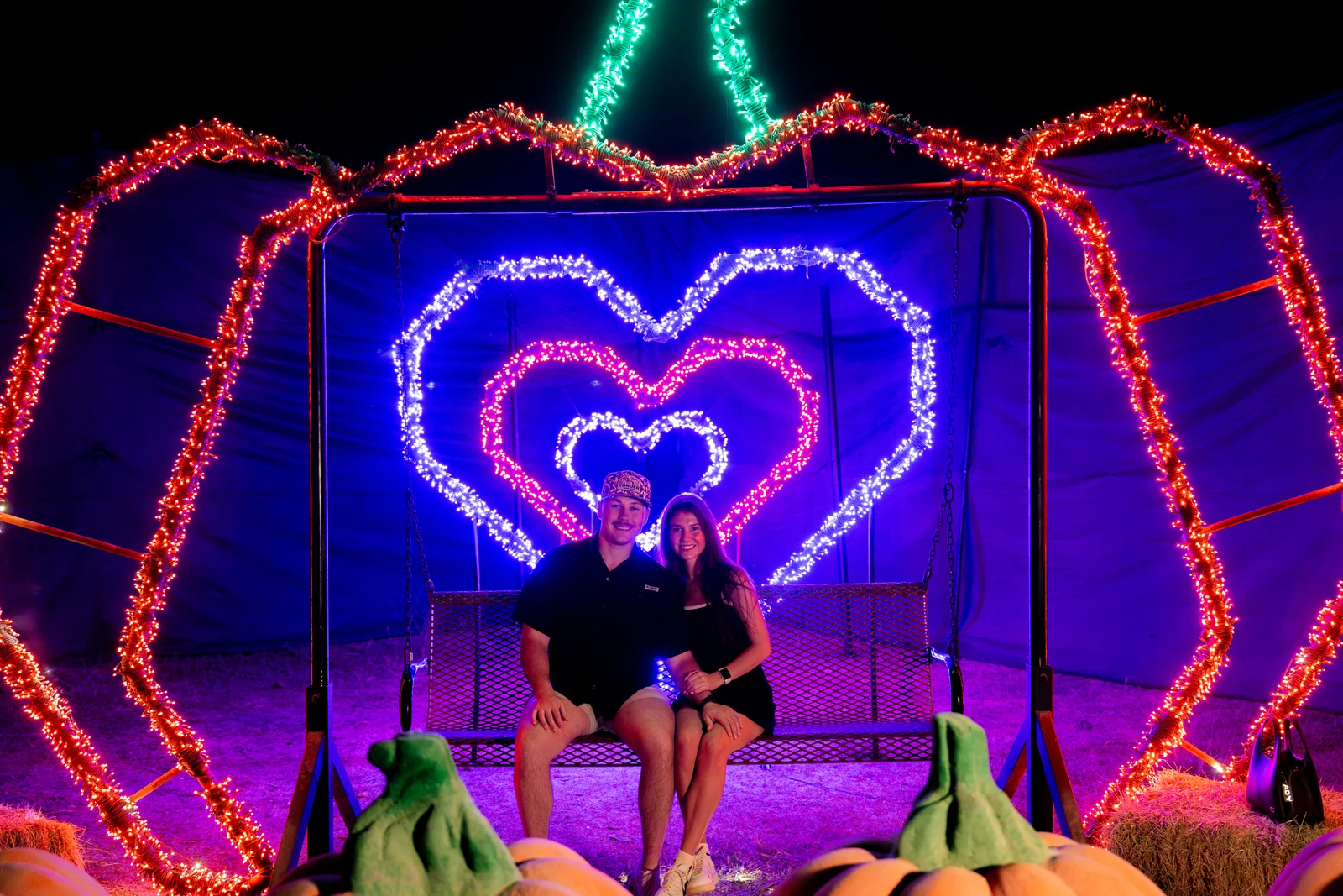 A couple on the swing beneath the glowing hearts of Lovers Lounge